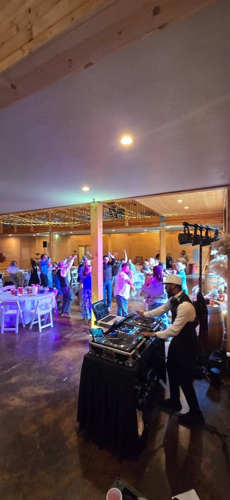 DJ187 performing while wedding guests dance at a barn venue reception