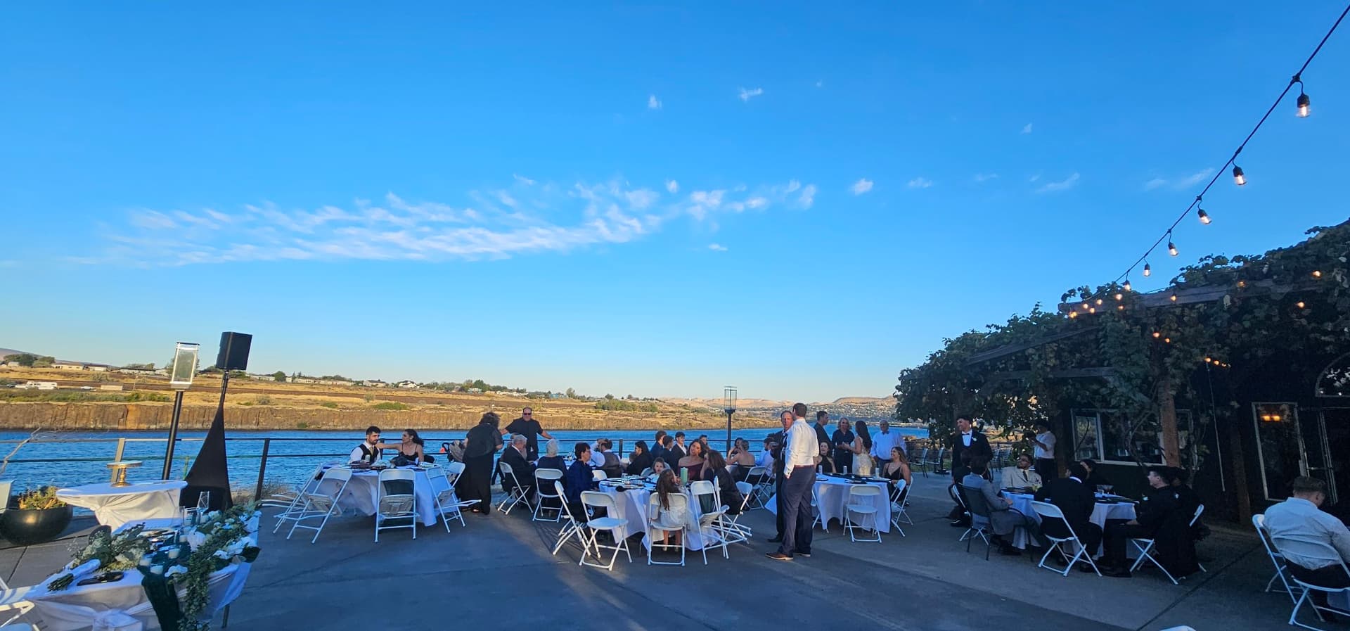 Outdoor wedding reception at dusk with guests at long tables