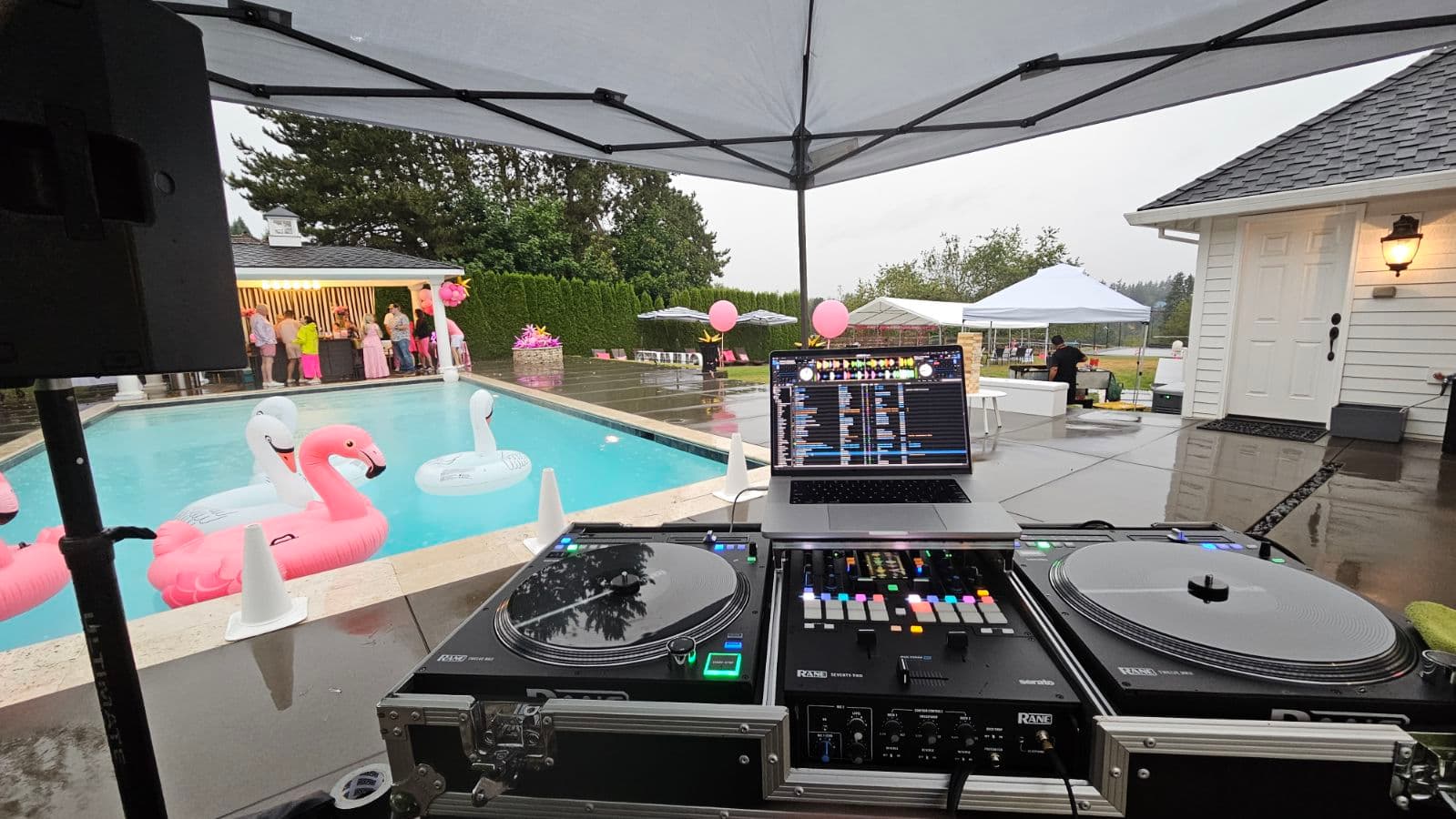 Guests dancing outdoors at a pool party with a DJ setup nearby